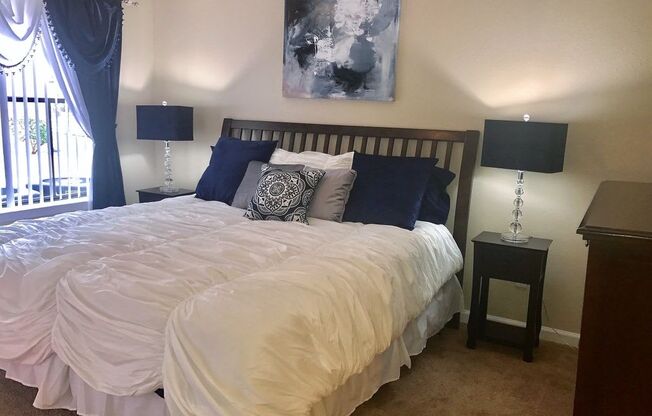 a bedroom with a large bed with a white comforter and blue pillows