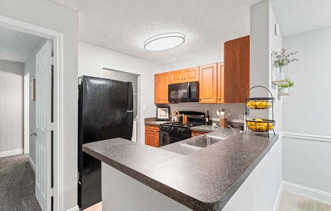 A kitchen with a black refrigerator and wooden cabinets.