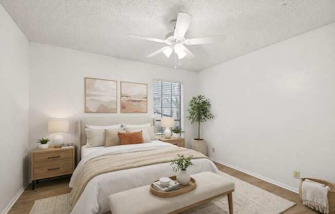 A bedroom with a bed, nightstand, and a plant.