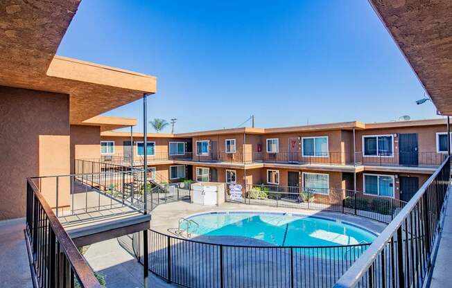 A pool in a courtyard surrounded by a black fence.