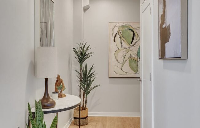 a hallway with white walls and a white table with a lamp on it