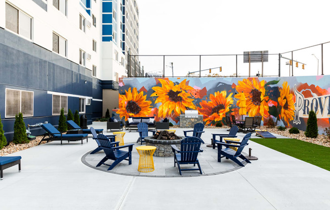 a patio with blue chairs and yellow tables and a mural of sunflowers