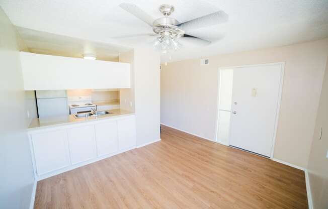 an empty living room with white cabinets and a ceiling fan