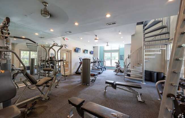 a gym with weights and cardio equipment and a spiral staircase