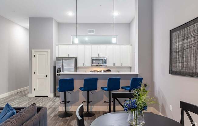 A modern kitchen with blue chairs and a dining table.