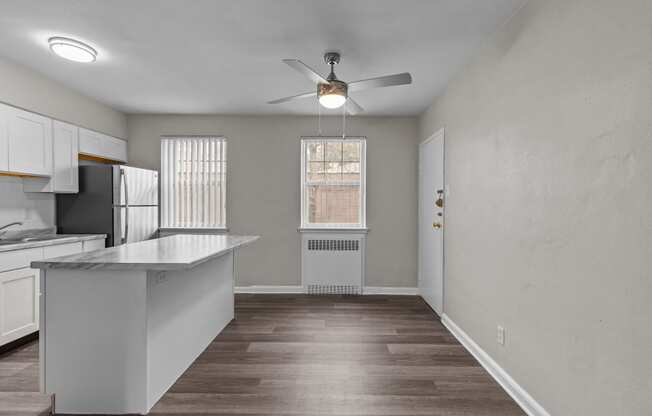 an empty kitchen with an island and a ceiling fan