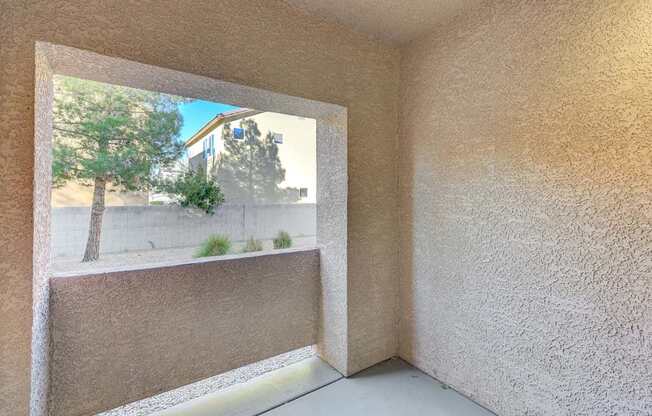 A room with a window showing a tree and a building outside.