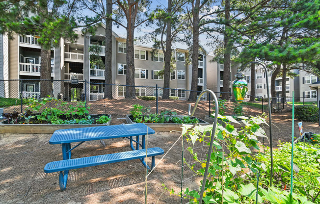 a blue picnic table in a garden in front of an apartment building