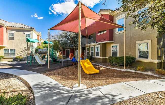 A playground with a red umbrella and a yellow slide.