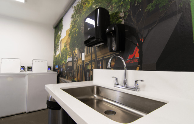 A modern kitchen with a stainless steel sink and a wall-mounted speaker.