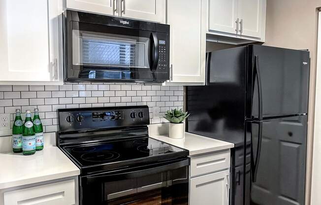 a kitchen with black appliances and white cabinets and a black refrigerator