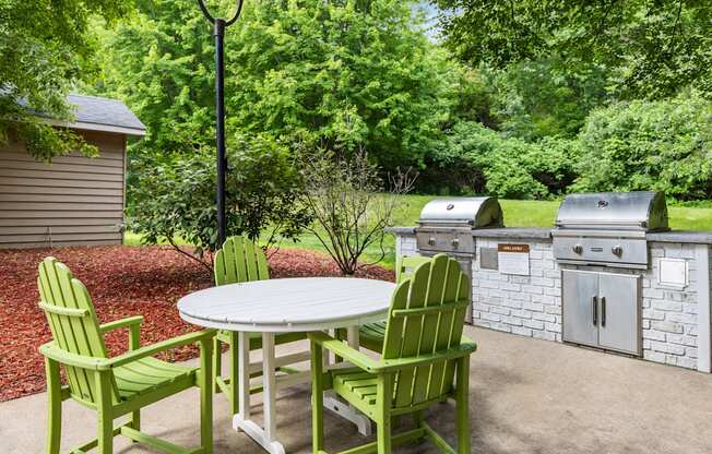 A white table with green chairs is in the middle of a patio.