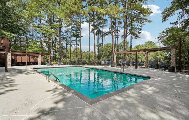 A swimming pool surrounded by trees and a wooden structure.