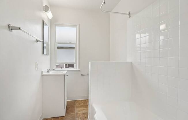 A white bathroom with a shower, sink, and mirror.
