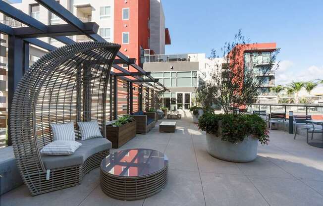 A patio with a wicker chair and table.