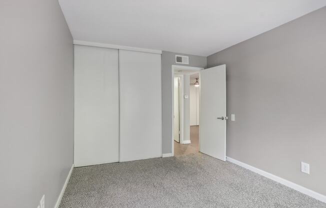 a bedroom with white closet doors and a carpeted floor