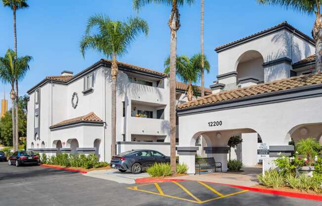 a white building with a parking lot and palm trees