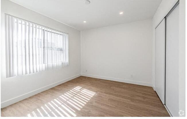 an empty living room with a large window and wooden floors