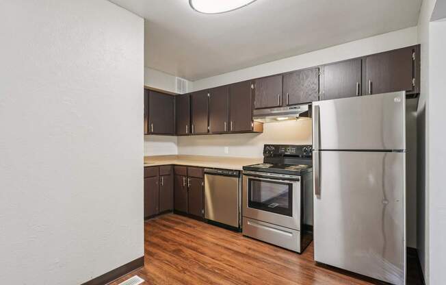 A kitchen with a refrigerator, oven, and stove.