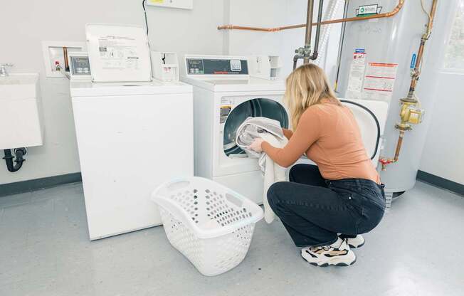 A woman is doing laundry in a laundromat.