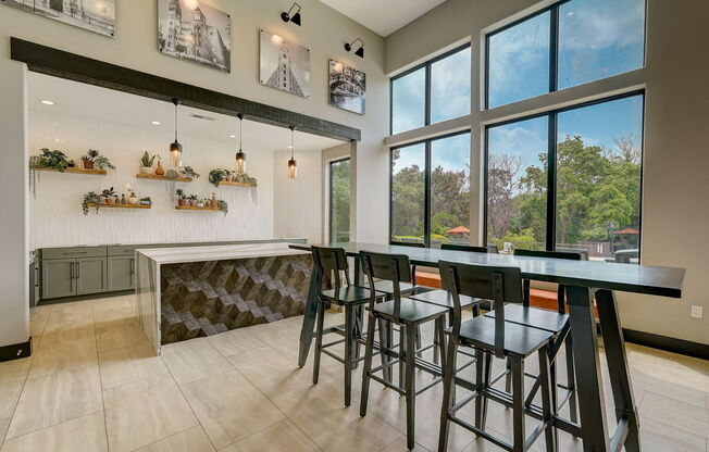 a bar with stools in a kitchen with large windows