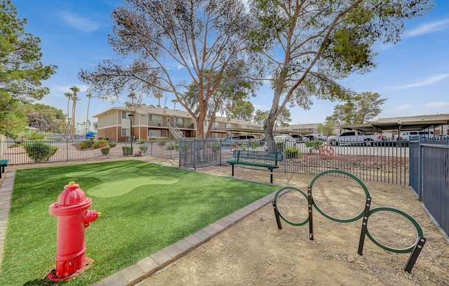A red fire hydrant sits on a green lawn next to a playground.