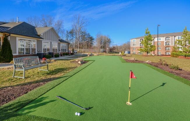 a putting green in front of a house with a golf ball on it
