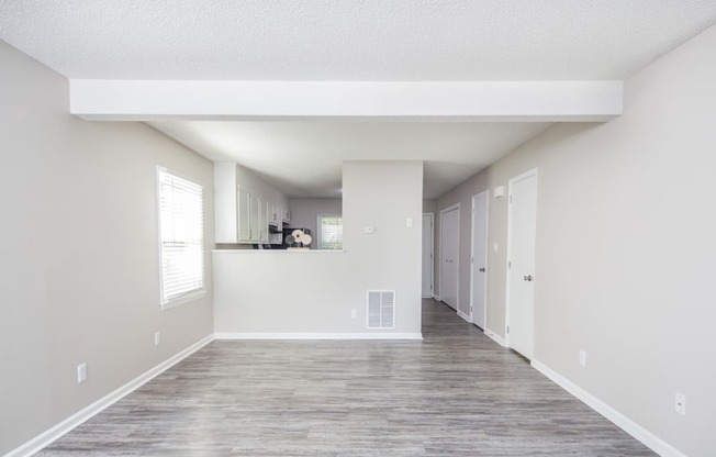 an empty living room with white walls and a wood floor