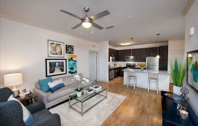 A living room with a grey couch and a glass coffee table.