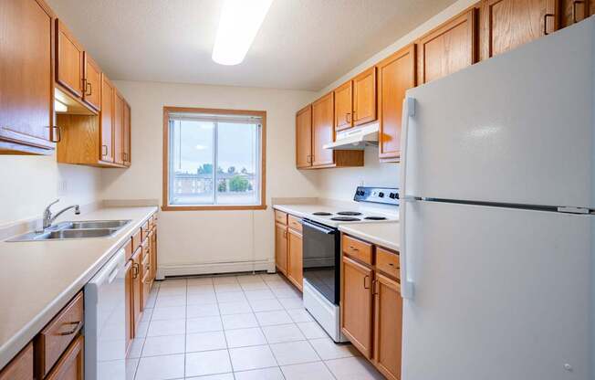 A kitchen with white appliances and wooden cabinets. Fargo, ND Summit Point Apartments