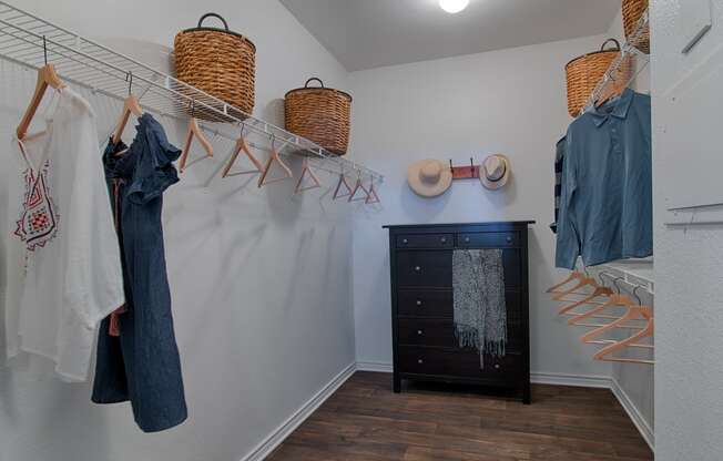 a walk in closet with a dresser and hangers