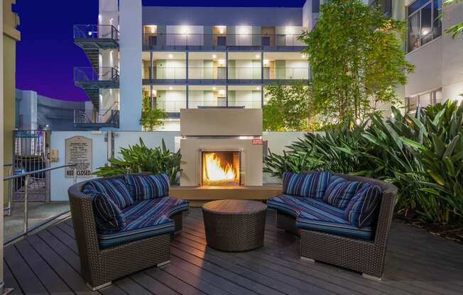 Fireplace on a patio with chairs and a table at sunset and vine