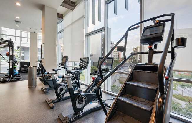 A gym with a treadmill, elliptical machines and a stair climber.