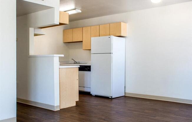 Kitchen with White Appliances, Blonde Wood Cabinets and White Counters