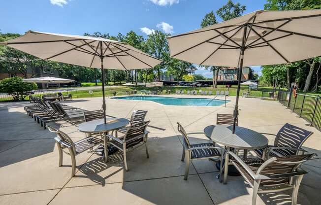 A poolside area with tables and chairs and umbrellas.