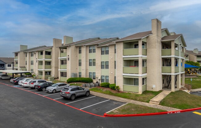 a large apartment building with cars parked in a parking lot