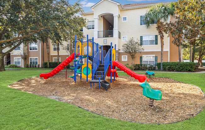 a playground with slides in front of an apartment building