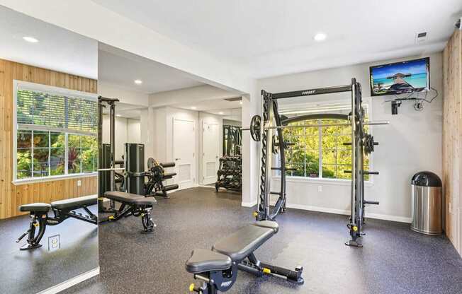 Fitness center with a variety of equipment including a bench, weights, and a television.