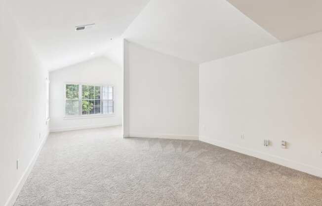 A spacious living room with a carpeted floor and a window.
