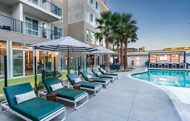 Relax by the resort-style pool at Modera Pomona, featuring a lounge area, seating, and palm trees.