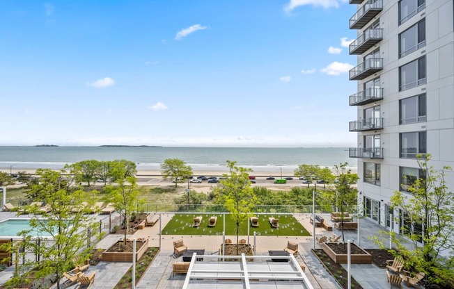 A view of a rooftop patio with a pool and a building in the background.