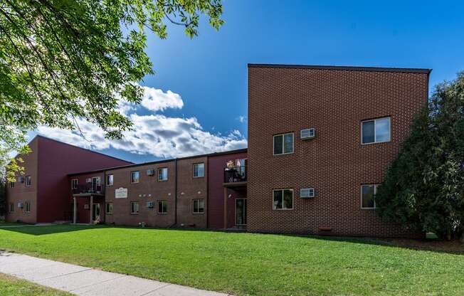 an exterior view of a brick apartment building with green grass. Fargo, ND Crescent Park Apartments.