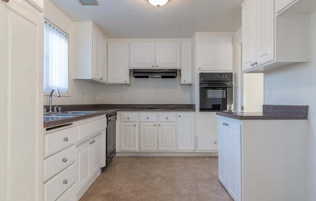 a kitchen with white cabinets and black counter tops at Park Avenue Apartments, Long Beach ,90815