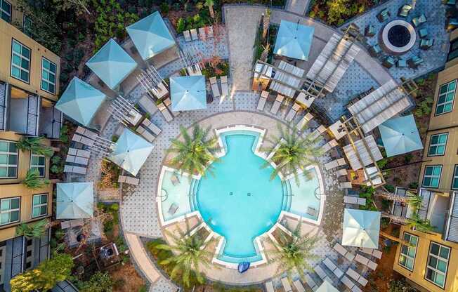 A round swimming pool surrounded by a white fence and palm trees.