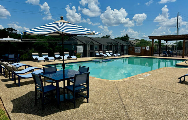 a swimming pool with a table and chairs and an umbrella