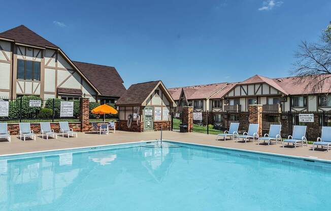 A large swimming pool in front of a building with lounge chairs around it.