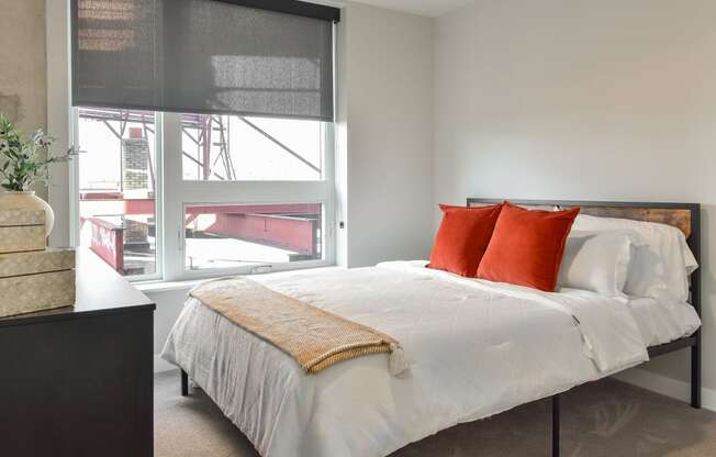 a bedroom with a large window and a bed with red pillows at The Bohen Apartments , Minnesota, 55408