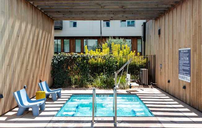 A small pool with a diving board and two chairs.