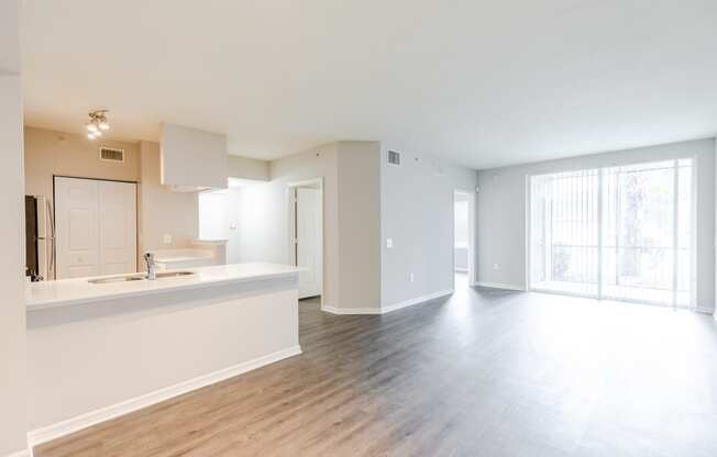 a kitchen and living room with hardwood floors and a sliding glass door to a balcony at Heritage Bay, Jensen Beach, FL