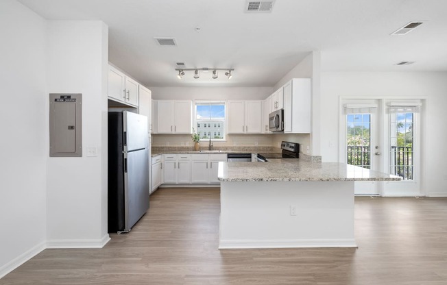 a kitchen with white cabinets and a large island with granite countertops